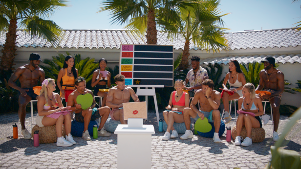 Kandidaten sitzen im Freien und nehmen an einer Paarungszeremonie für „Love Island“ teil.