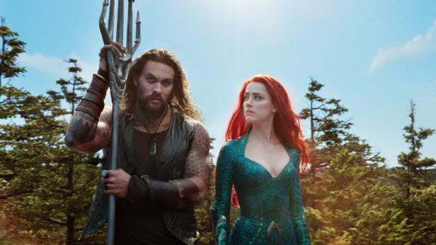 Jason Momoa als Aquaman und Amber Heard als Mera vor einem bewaldeten Hintergrund.