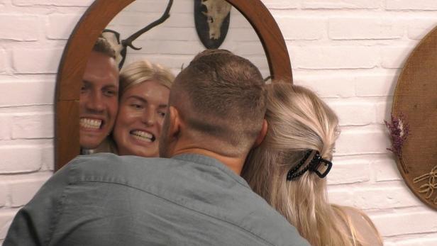 Ein Paar macht ein Selfie im Spiegel, während ein Mann sie umarmt.