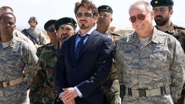 Robert Downey Jr., in Anzug, steht mit US-Luftwaffenangehörigen zusammen.
