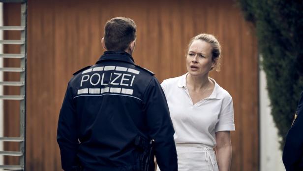 Eine besorgte Frau spricht mit einem Polizisten.