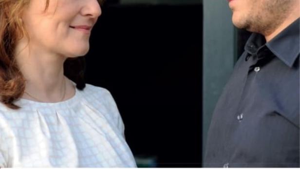 Eine Frau und ein Mann sehen sich vor dem Hintergrund des Logos von „Das Erste“ an.