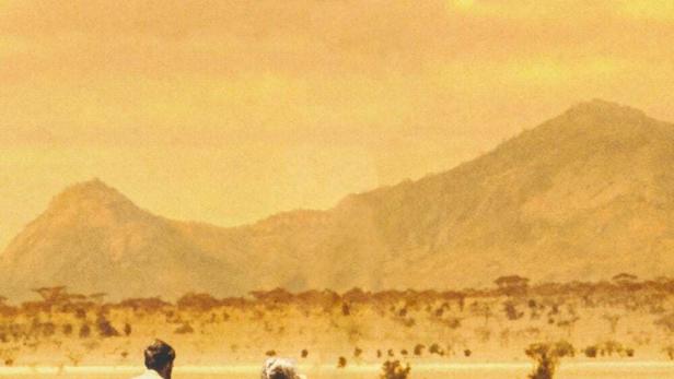 Das Filmplakat für „Frei geboren – Eine Königin für Afrika“ zeigt ein Paar mit einem Löwen in der afrikanischen Savanne.