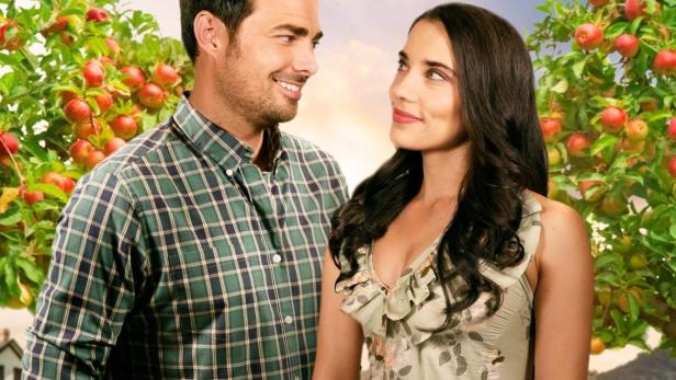 Ein Mann und eine Frau stehen vor Apfelbäumen auf dem Filmplakat zu „A Country Romance“.