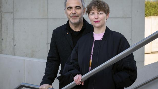 Ein Mann und eine Frau stehen auf einer Treppe vor einer Betonwand.