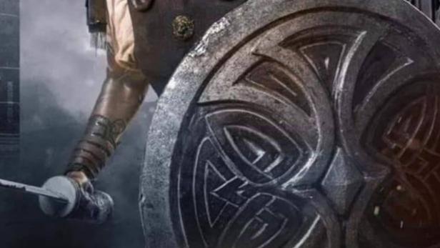 Ein Mann in Rüstung hält ein Schwert und einen Schild, vermutlich eine Filmszene.