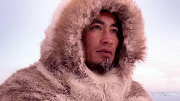 Ein Mann in traditioneller Kleidung vor dem Hintergrund des Films „The Last Ice“ von National Geographic.