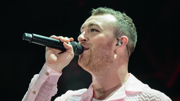 Sam Smith singt mit einem Mikrofon in der Hand.
