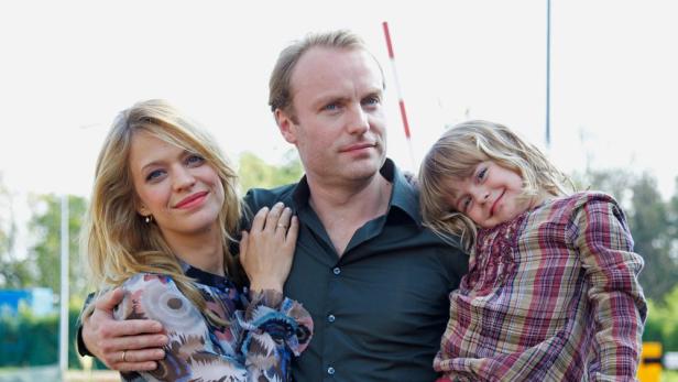 Eine Familie steht zusammen und lächelt in die Kamera.