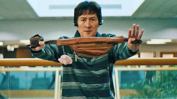 Ke Huy Quan hält in „Everything Everywhere All at Once“ eine Bauchtasche hoch.