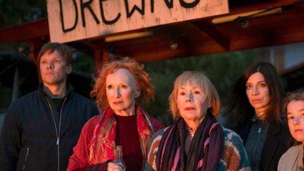 Eine Gruppe von Menschen steht unter einem Schild mit der Aufschrift „Drewins“.