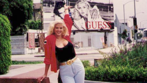 Anna Nicole Smith posiert vor einer Guess-Werbetafel.