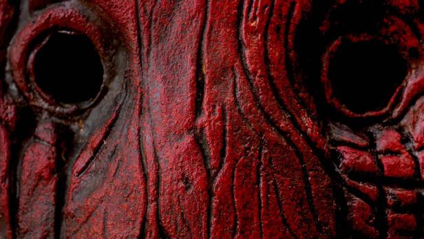 Das rote, verzerrte Gesicht einer Horrorfilmfigur „Slasher“.