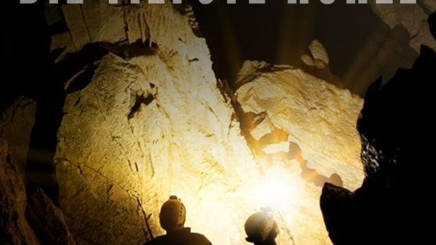 Zwei Personen erkunden mit Stirnlampen eine dunkle Höhle.