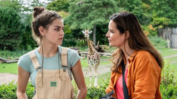 Zwei Frauen unterhalten sich im Zoo Leipzig, im Hintergrund eine Giraffe.