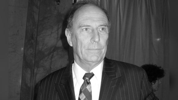 Ein Porträt von Paxton Whitehead in einem gestreiften Anzug und einer Krawatte.