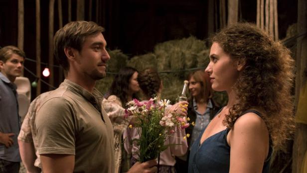 Ein Mann überreicht einer Frau einen Blumenstrauß auf einer ländlichen Feier.