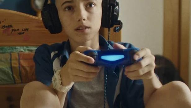 Ein junger Mann mit Kopfhörern spielt Videospiele mit einem Controller.
