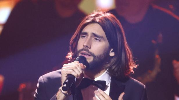 Álvaro Soler singt in einem schwarzen Anzug auf der Bühne.