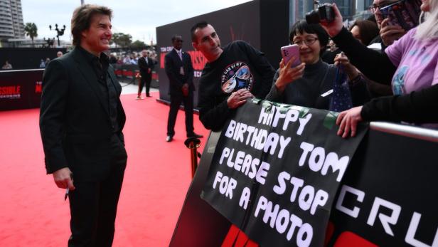 Tom Cruise posiert auf dem roten Teppich für Fans mit einem Geburtstagsplakat in Sydney.