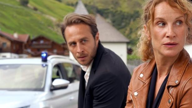 Ein Mann und eine Frau vor einem Polizeiauto in den Bergen, möglicherweise eine Szene aus „Bozen-Krimi“.