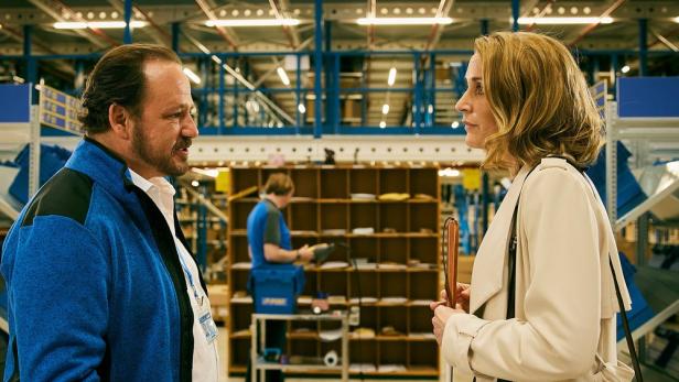 Zwei Personen unterhalten sich in einem Lagerraum.