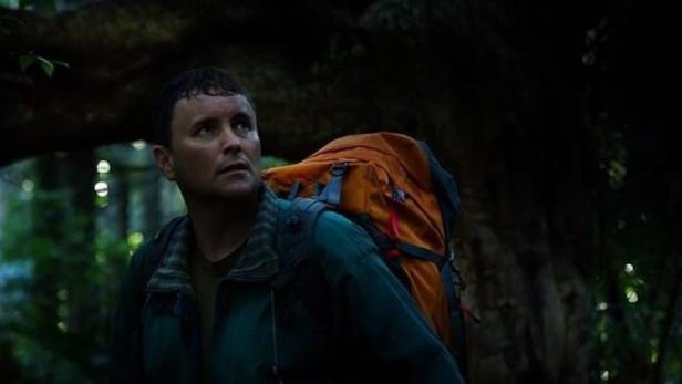 Ein Mann mit Rucksack blickt im Filmposter von „Loop Track“ nach oben.