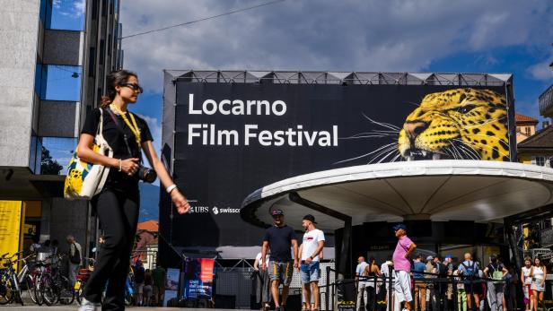 Besucher auf dem Locarno Film Festival Gelände vor einem großen Plakat mit einem Leoparden.