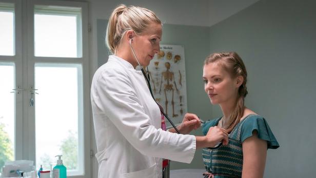 Eine Ärztin untersucht eine junge Patientin mit einem Stethoskop.