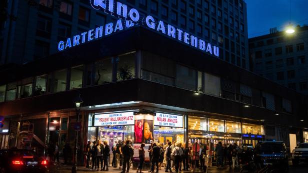 Menschen stehen vor dem Kino Gartenbau in der Nacht.