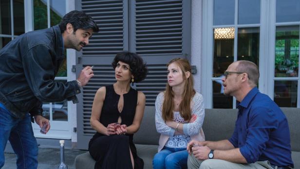 Vier Personen sitzen auf einer Terrasse und unterhalten sich bei Getränken.