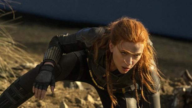 Scarlett Johansson als Black Widow in einem schwarzen Kampfanzug kriecht über unebenes Gelände.