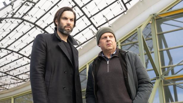 Zwei Männer stehen vor einem modernen Gebäude.