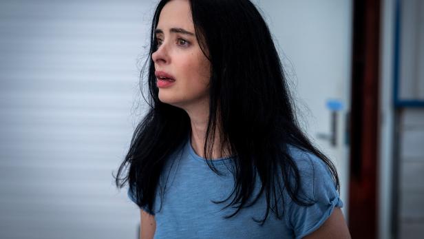 Schauspielerin Krysten Ritter ist in einem blauen Shirt zu sehen. Sie blickt verzweifelt von der Kamera weg.