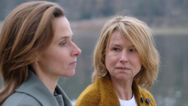 Zwei Frauen stehen vor einem unscharfen Hintergrund im Freien.