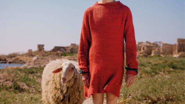 Das Filmplakat für „Misericordia“ zeigt einen Mann im roten Kleid und ein Schaf vor einer Ruinenlandschaft.