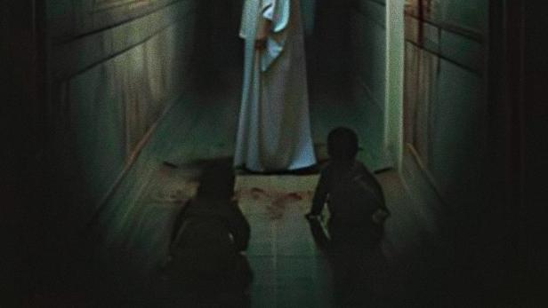 Eine Frau in Weiß steht in einem dunklen Flur, Titel des Films ist „A Semente do Mal“.