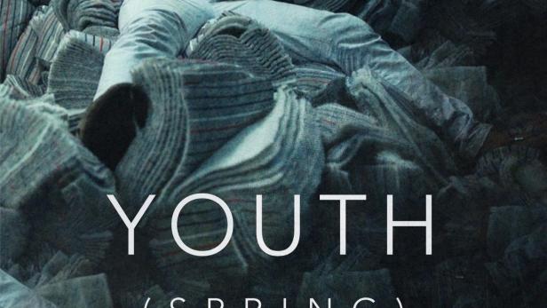 Ein Mann liegt auf einem Stapel gefalteter Stoffe, vermutlich ein Filmplakat für „Youth (Spring)“.