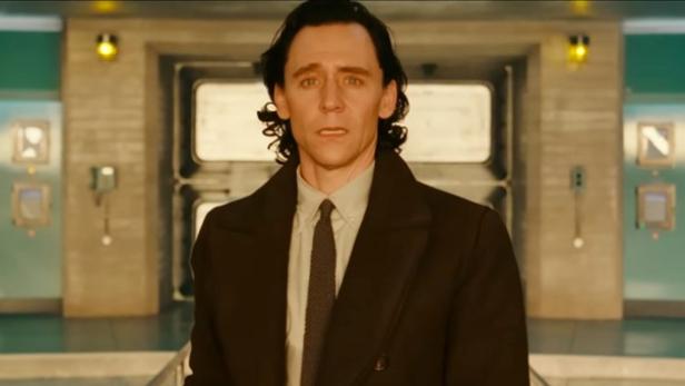 Tom Hiddleston blickt als Loki im Anzug in die Kamera