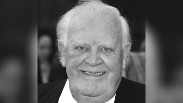 Joss Ackland lächelt auf einem Schwarz-Weiß-Foto. 