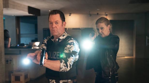 Zwei Polizisten, ein Mann und eine Frau, zielen mit gezogenen Waffen.