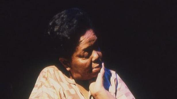 Porträt der kapverdischen Sängerin Cesária Évora mit einem Mikrofon in der Hand.