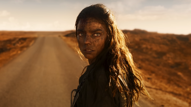 Anya Taylor-Joy steht mit verschmutztem Gesicht auf einer Straße in einer Wüste