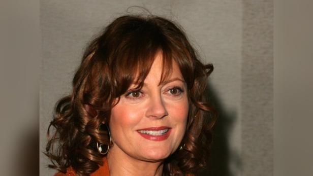 Porträt von Susan Sarandon mit lockigem, braunem Haar und Ohrringen.