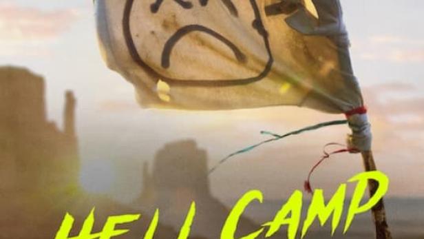 Das Filmplakat für „Hell Camp: Teen Nightmare“ zeigt eine Wüstenlandschaft mit einer Flagge, auf der ein trauriges Gesicht gezeichnet ist.