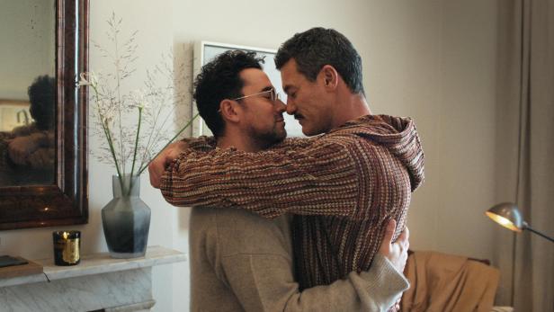 Zwei Männer umarmen sich liebevoll in einem Wohnzimmer