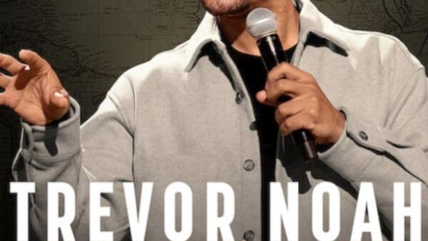 Trevor Noah hält ein Mikrofon in der Hand, im Hintergrund eine Weltkarte für seine Show „Where Was I“.