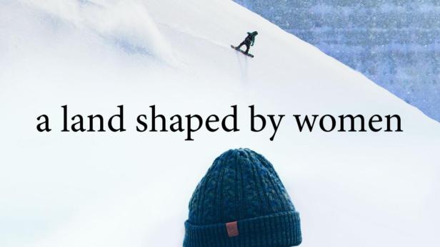 Eine Frau mit Mütze steht vor einer verschneiten Berglandschaft mit Snowboardern.