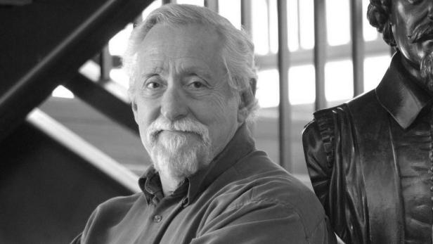 Ein Schwarzweißporträt von Mike Nussbaum neben einer Statue.