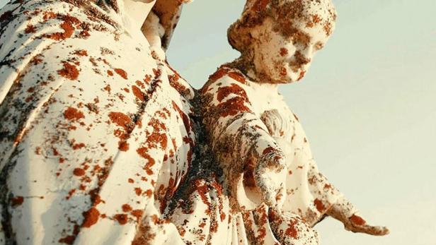 Eine Statue der Jungfrau Maria mit dem Jesuskind, bedeckt mit Flechten.